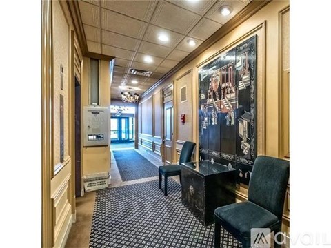 A hallway with a black and white checkered floor, a black chair, and a large painting on the wall.