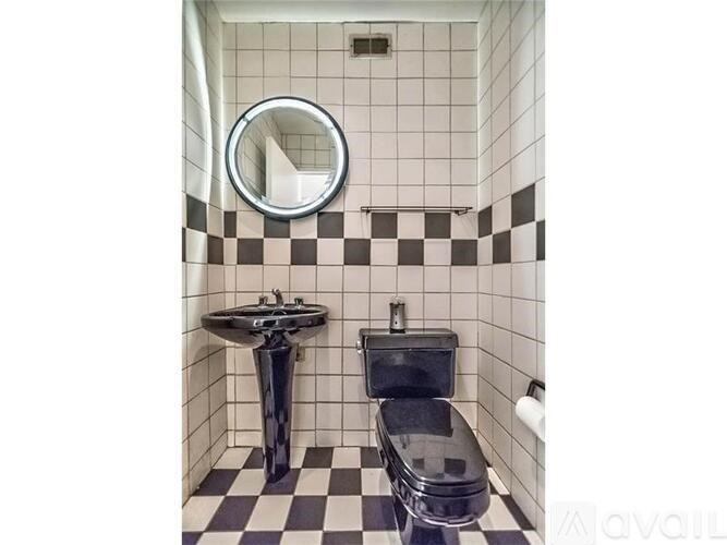 A black and white checkered bathroom with a round mirror.
