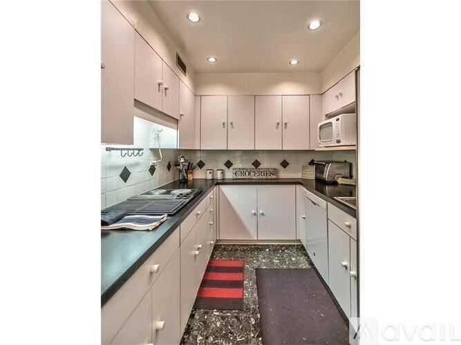 A kitchen with white cabinets and a black counter top.