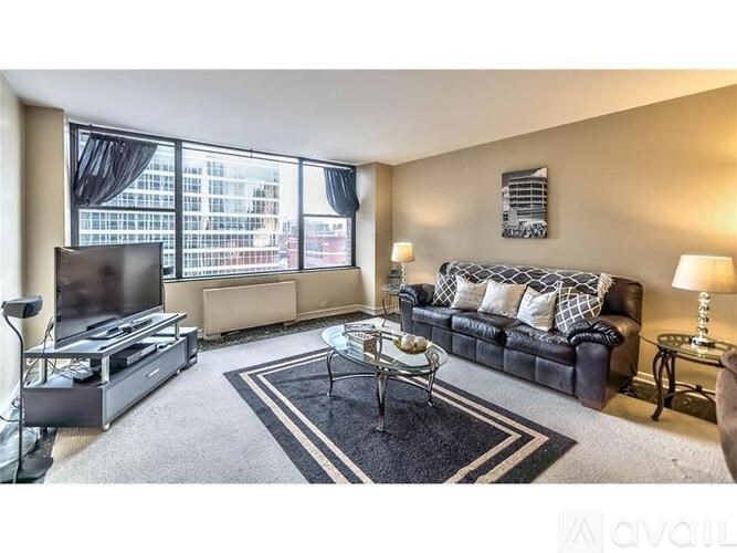 A living room with a black couch, a coffee table, and a television.