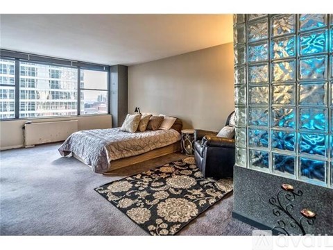 A bedroom with a large bed and a glass block wall.