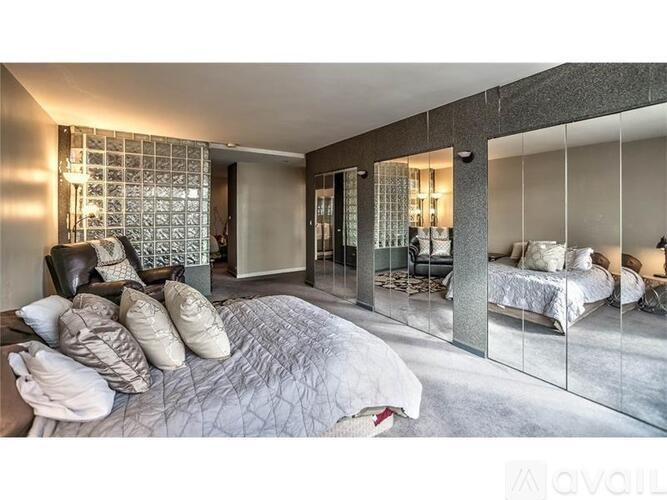 A bedroom with a large bed and a mirrored wall.