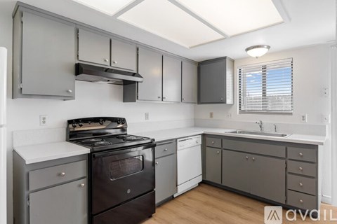 A kitchen with a black stove top oven and white cabinets.
