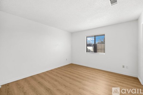 A room with wooden flooring and a window with blinds.
