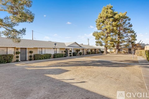 A parking lot with a building and trees in the background.