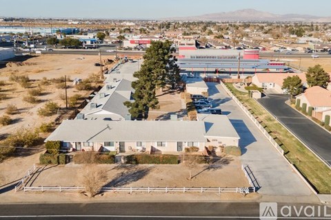 A large building with a grey roof is surrounded by a fence and a parking lot.