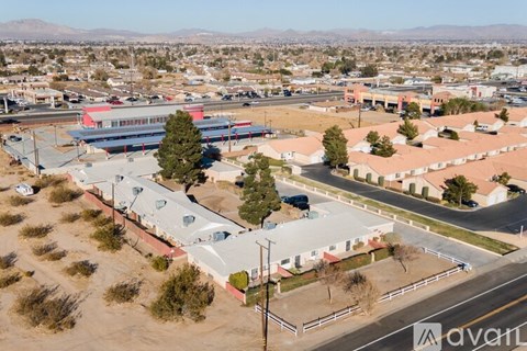 A large building with a red roof is surrounded by a parking lot.