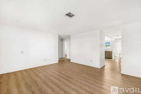 A spacious room with wooden flooring and white walls.
