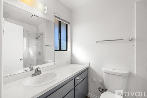 A bathroom with a sink, mirror, toilet and a window.
