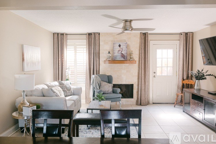 A living room with a fireplace, chairs, and a painting on the wall.