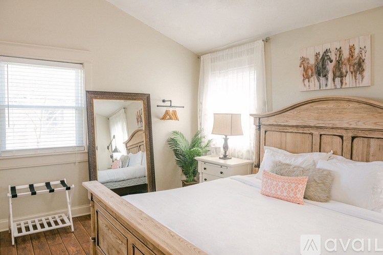 A bedroom with a large bed, a mirror, a lamp, and a plant.