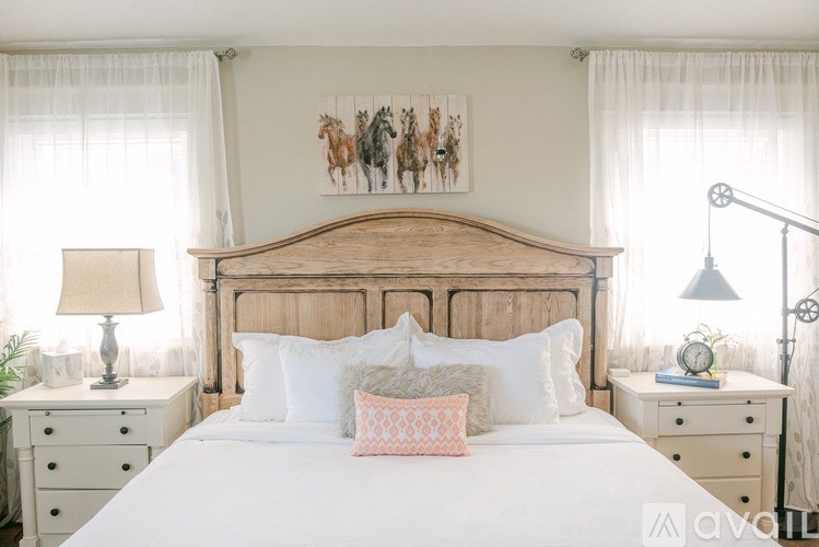 A bedroom with a large bed, two nightstands, and a painting on the wall.