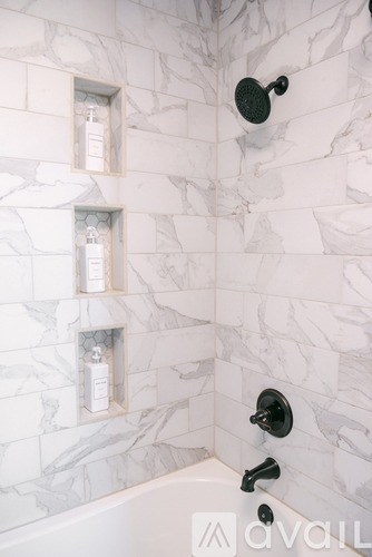 A white marble tiled shower with black fixtures.