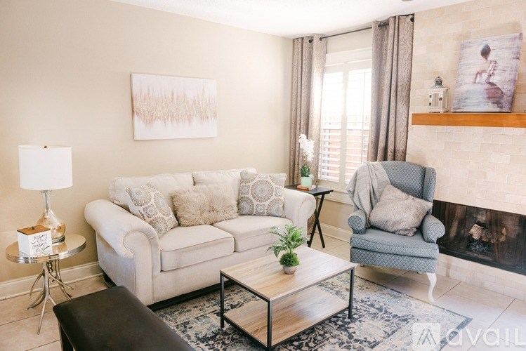 A living room with a white couch, a grey armchair, a coffee table, and a painting on the wall.