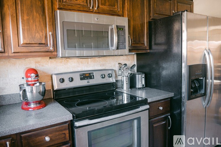 A kitchen with a black refrigerator, black stove, and wooden cabinets.