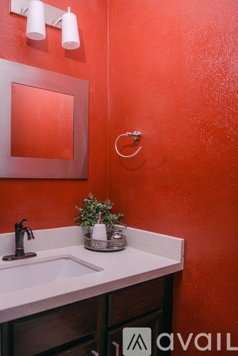 A bathroom with a red wall and a white sink.