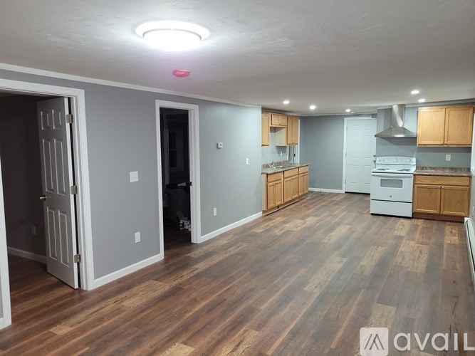 A kitchen with wooden floors and a person standing in the doorway.