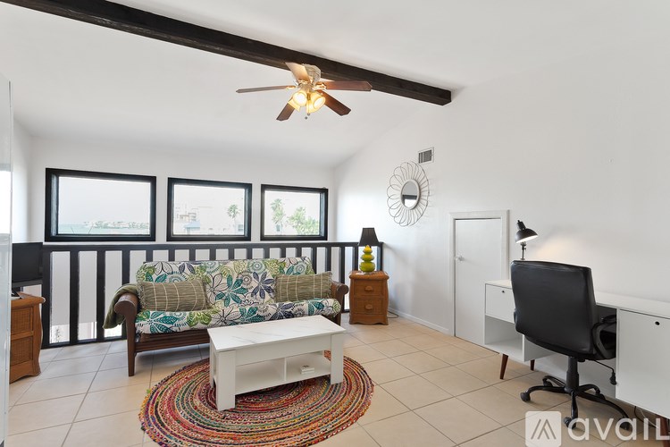 A living room with a couch, a chair, a table, and a ceiling fan.