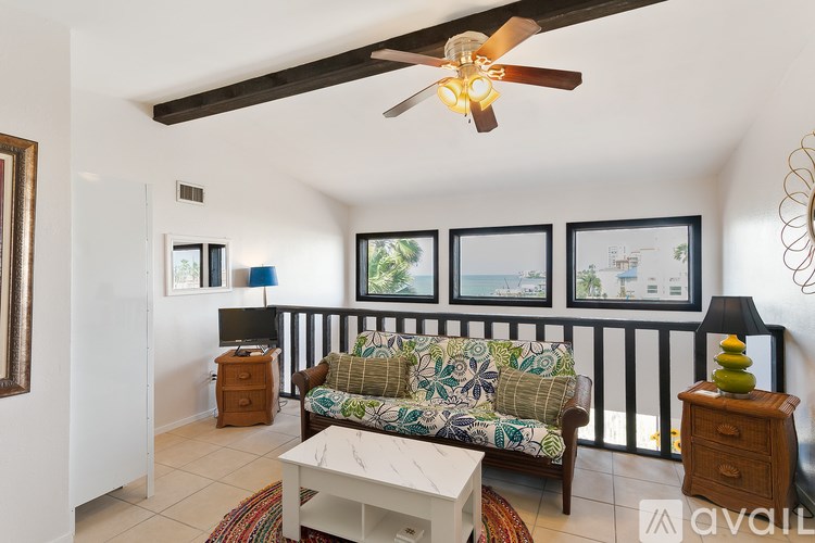 A living room with a couch, a table, and a ceiling fan.