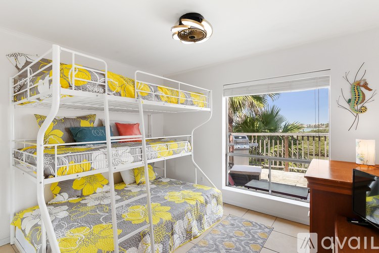 A room with bunk beds and a window overlooking a balcony.