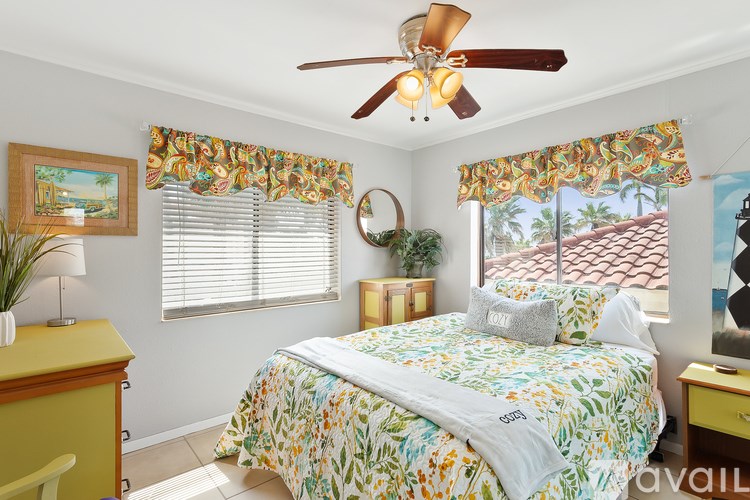 A bedroom with a bed, a ceiling fan, and a window with a view of a roof.