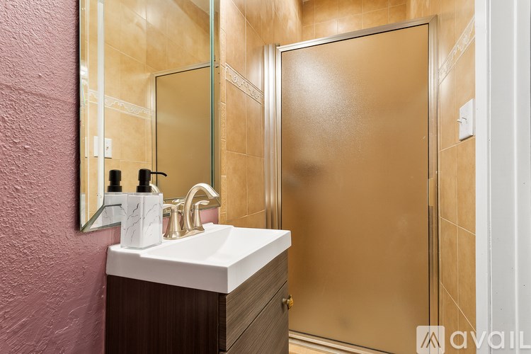 A bathroom with a sink, mirror, and shower.