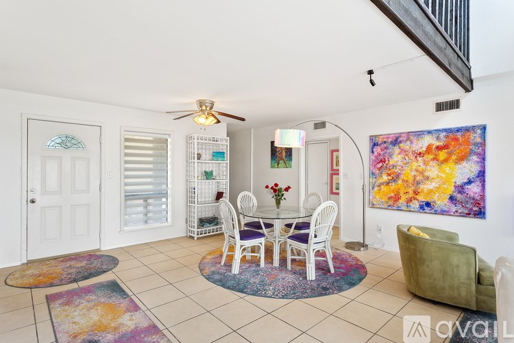 A living room with a white table and chairs, a ceiling fan, and a painting on the wall.