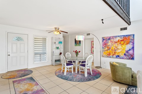 A living room with a white table and chairs, a ceiling fan, and a painting on the wall.