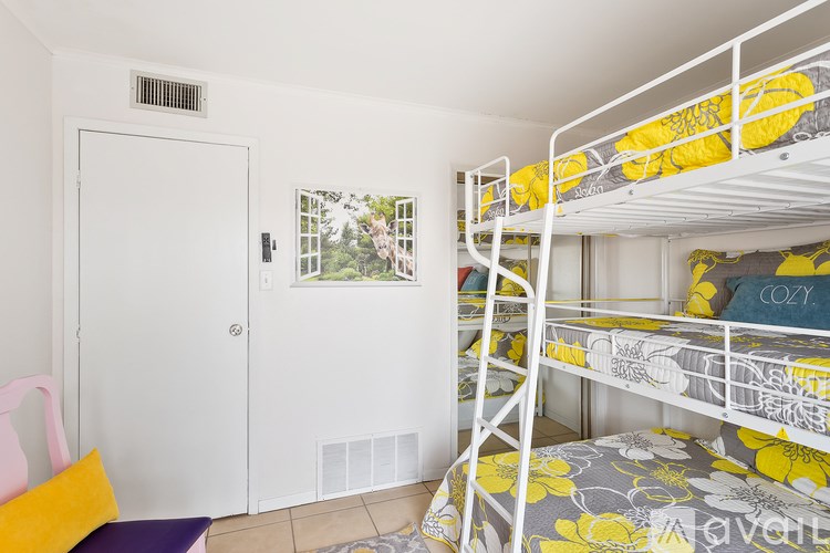 A white bunk bed with yellow pillows in a room with a white door.