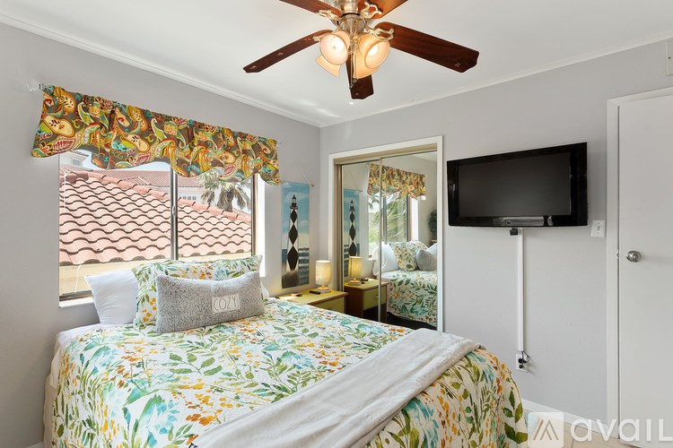 A bedroom with a bed, a ceiling fan, and a television.