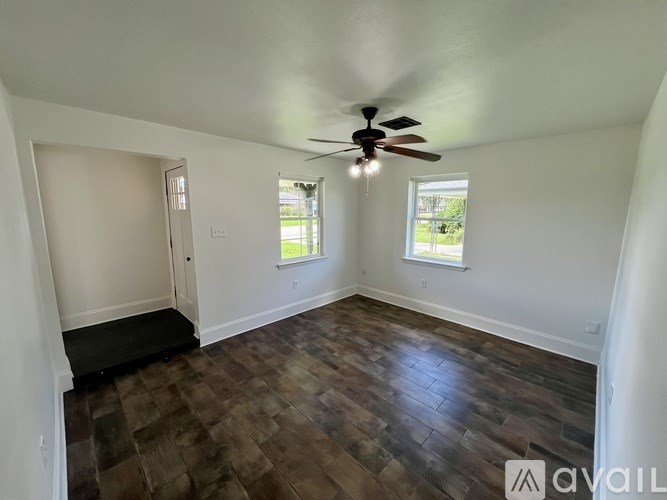 A room with a ceiling fan and wooden flooring.
