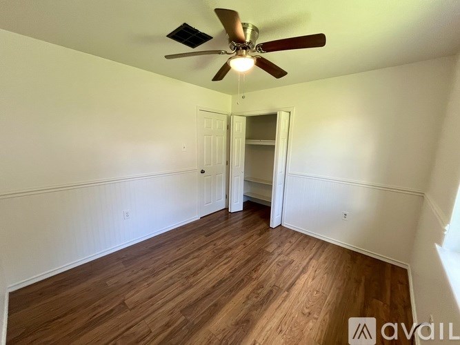 A room with a ceiling fan and wooden flooring.