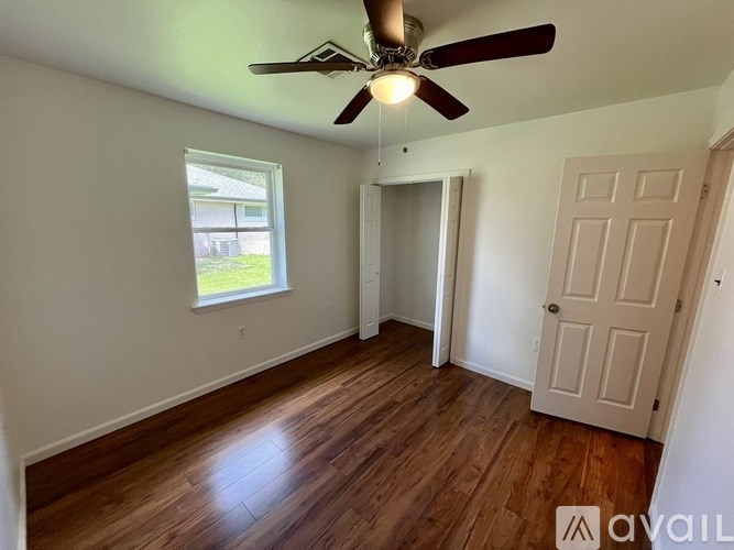 A room with a ceiling fan and wooden flooring.