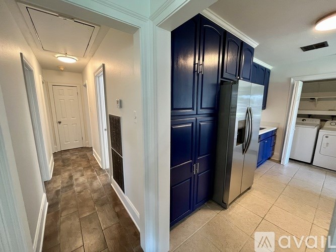 A kitchen with blue cabinets and a stainless steel refrigerator.