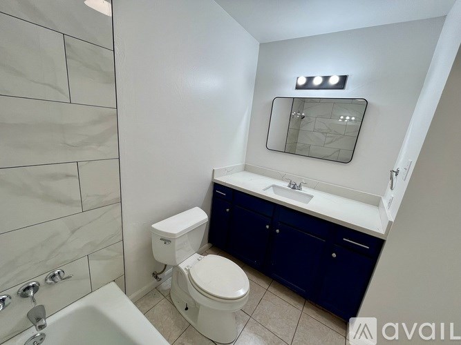 A white toilet sits in a bathroom with a white sink and a mirror above it.