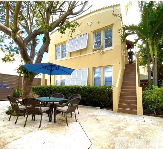 A patio with a table and chairs is set up outside a yellow building.