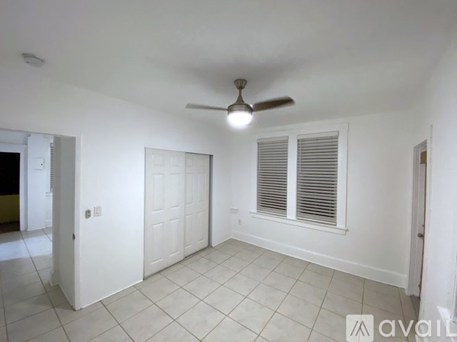 A room with a ceiling fan and a window with blinds.
