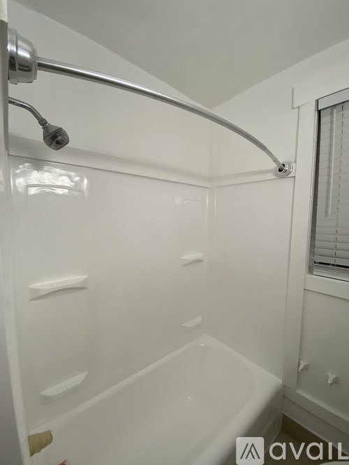 A white bathroom with a shower and a window.