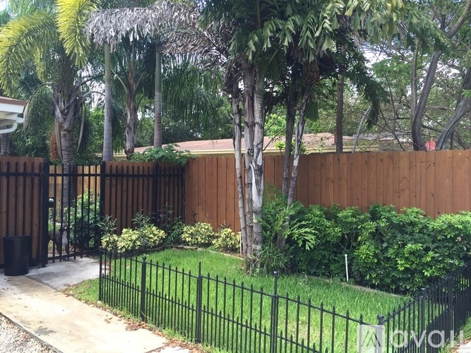 A black fence surrounds a green lawn.