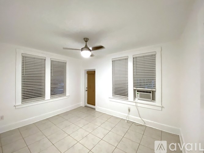A room with a ceiling fan and two windows with blinds.
