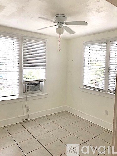 A room with a ceiling fan and two windows with blinds.