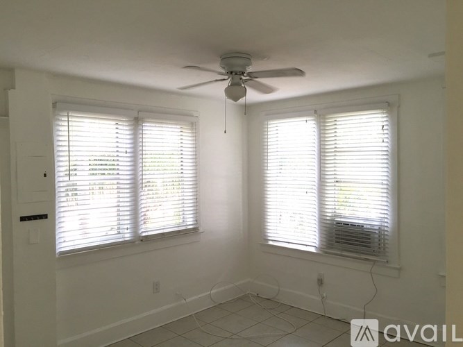 A room with a ceiling fan and two windows with blinds.