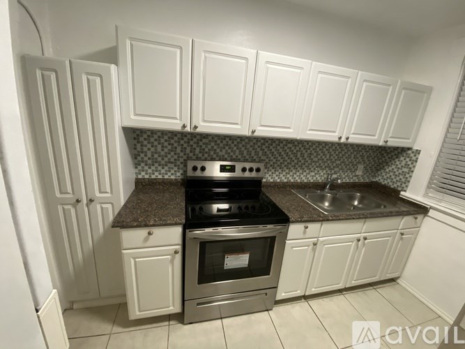 A kitchen with white cabinets and a granite countertop.