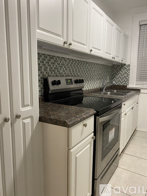 A kitchen with white cabinets and a black stove top oven.