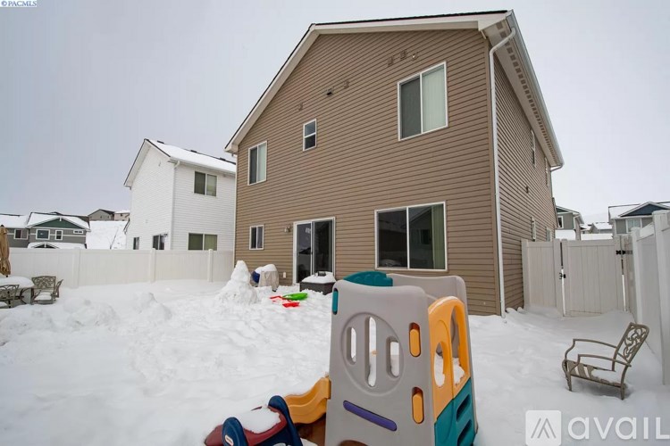A house with a snow-covered yard and a playpen in the foreground.