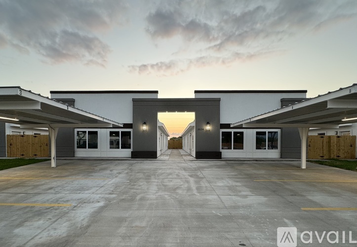 A parking lot with a building entrance and a cloudy sky.