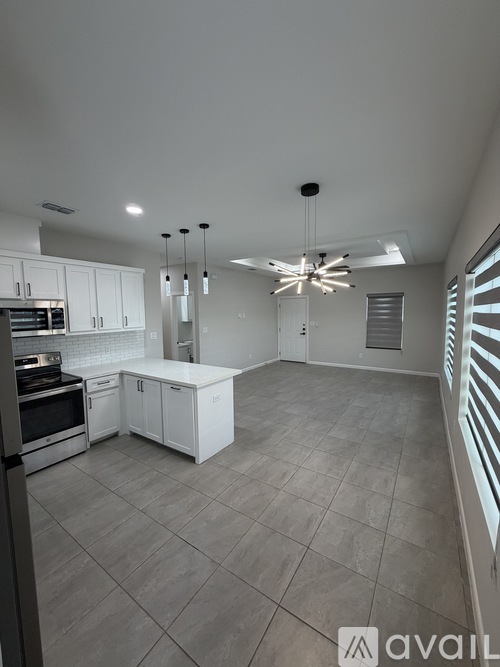 A spacious room with a ceiling fan and a kitchen area in the background.