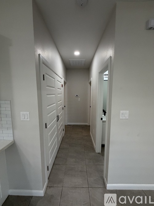 A long hallway with white walls and a grey floor.