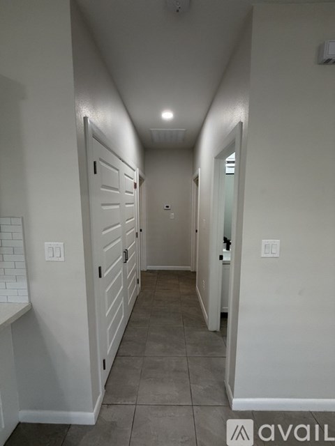 A long hallway with white walls and a grey floor.