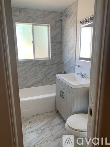 A bathroom with a marble tile wall and a white toilet.